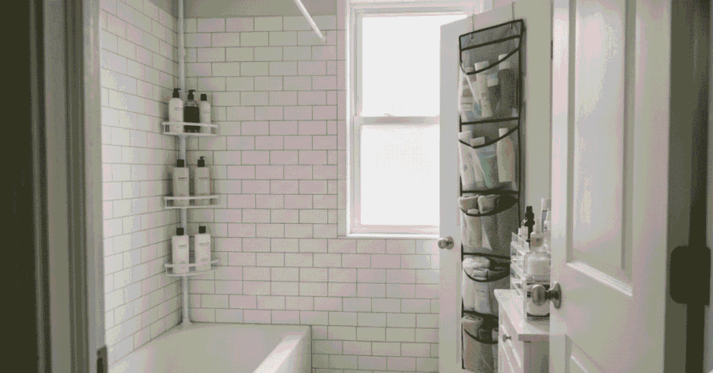 Small rental bathroom organized without drilling — tension shower caddy, over-door pocket organizer, and countertop tiered skincare storage